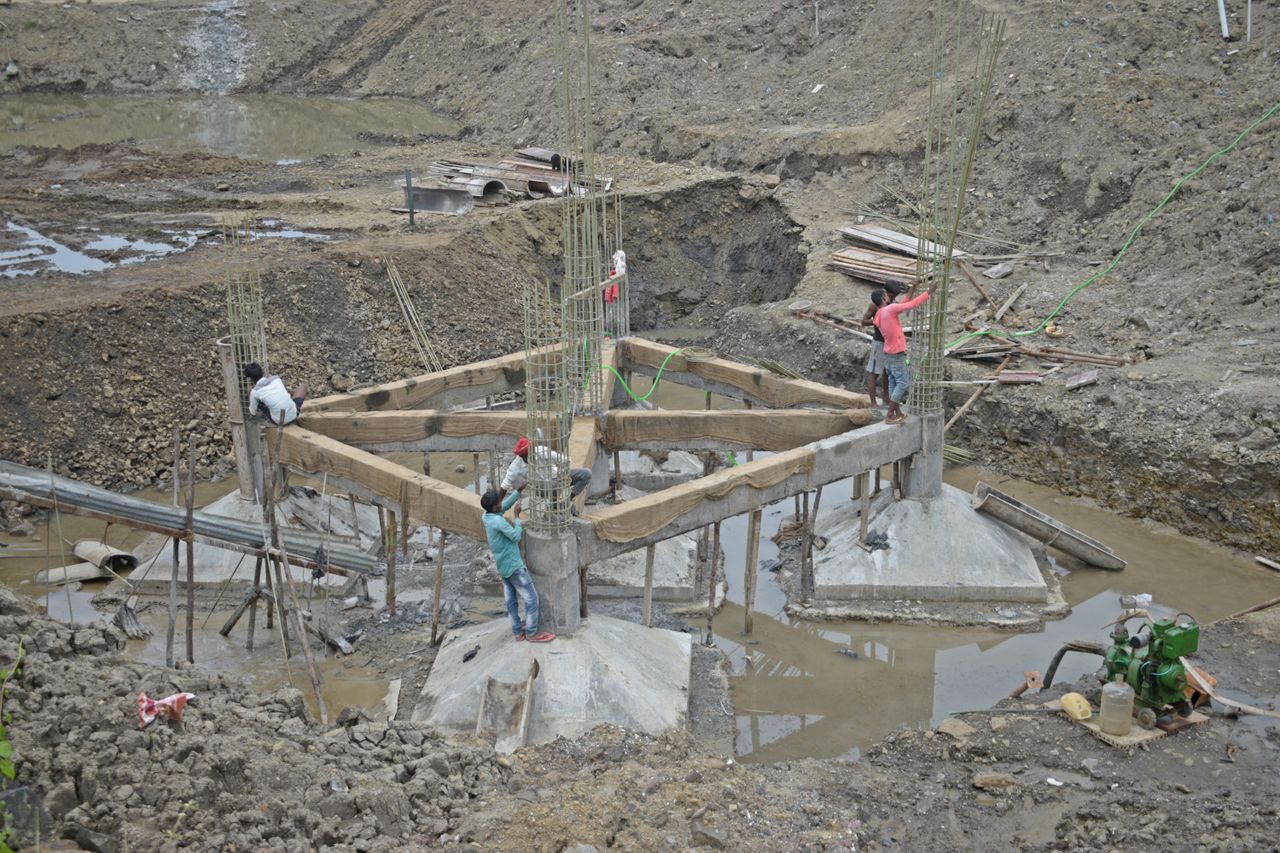 service-04 Workers constructing a building foundation with rebar and wooden supports outdoors.